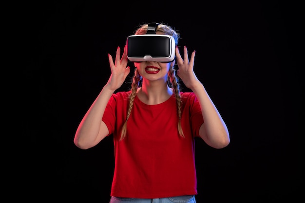 Vooraanzicht van jonge vrouw die virtual reality speelt op donkere muur