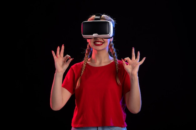 Vooraanzicht van jonge vrouw die virtual reality speelt op donkere muur