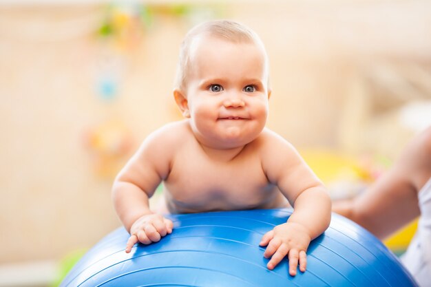 Vooraanzicht van kleine baby met lichte ogen die op grote blauwe geschiktheidsbal liggen