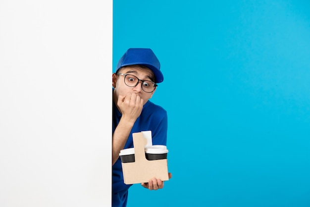 Vooraanzicht van mannelijke koerier in blauw uniform met koffie op het blauw