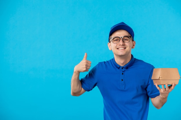 Vooraanzicht van mannelijke koerier in blauw uniform met weinig voedselpakket op blauw