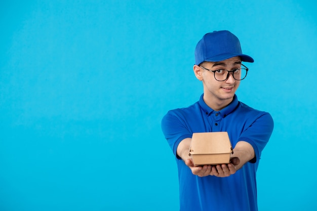 Vooraanzicht van mannelijke koerier in blauw uniform met weinig voedselpakket op blauw