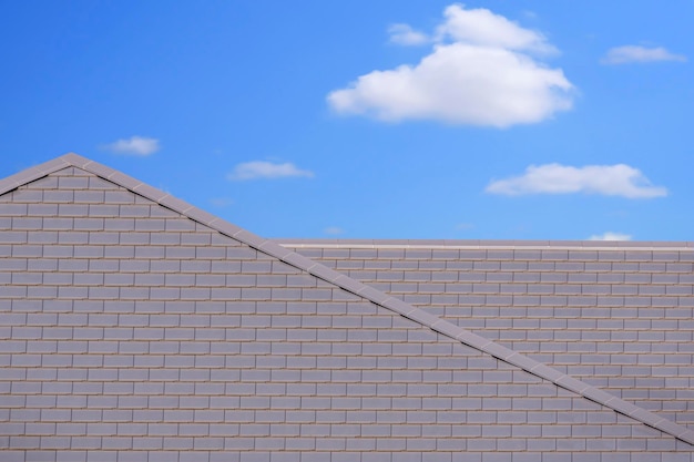 Vooraanzicht van modern plat betonnen grijs pannendak tegen witte wolk op blauwe hemelachtergrond