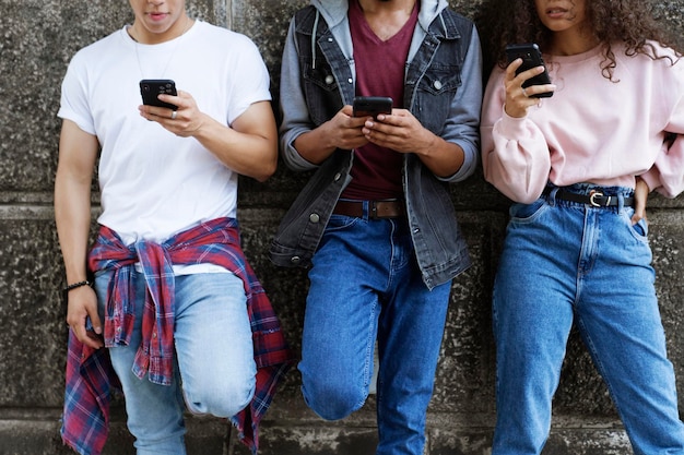 Vooraanzicht van onherkenbare jonge mensen die met mobiele telefoons staan