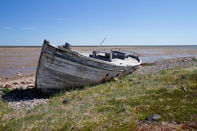 Foto vooraanzicht van oude houten boot gesloopt en gestrand op een rotsachtige kustlijn