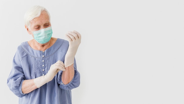 Vooraanzicht van oudere vrouw met medische masker en chirurgische handschoenen