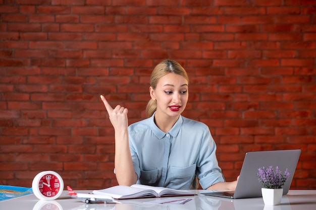 vooraanzicht van reisagent die achter haar werkplek zit en laptopbezetting gebruikt manager service binnenshuis assistent kaart toerisme wereldwijd