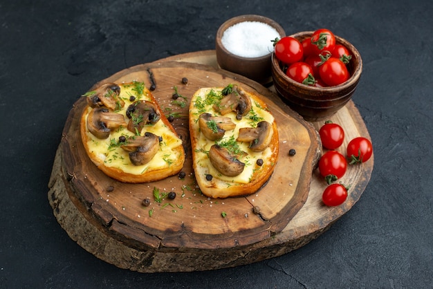 Vooraanzicht van smakelijke snack met champignons, tomaten, zout op een houten bord op zwarte achtergrond