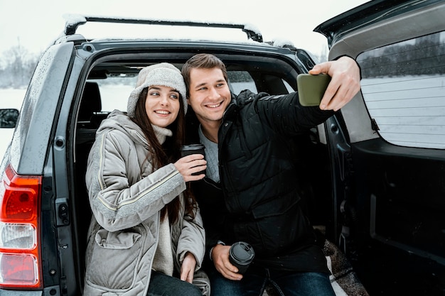 Foto vooraanzicht van smileypaar dat selfie tijdens een roadtrip neemt