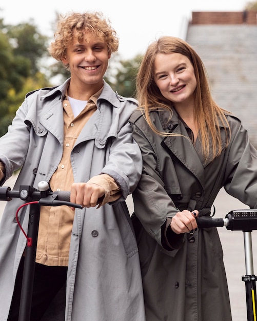 Vooraanzicht van smileypaar met behulp van elektrische scooter buitenshuis