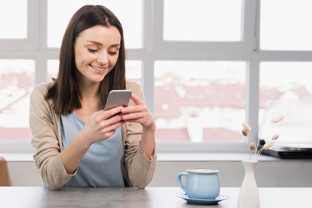 Foto vooraanzicht van vrouw bij smartphone van de bureauholding