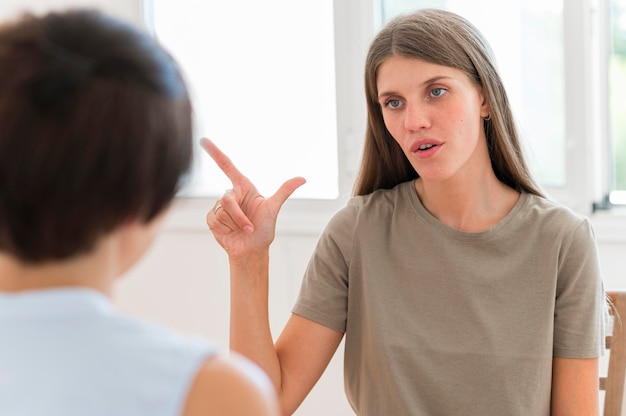 Foto vooraanzicht van vrouw die iemand de gebarentaal onderwijst