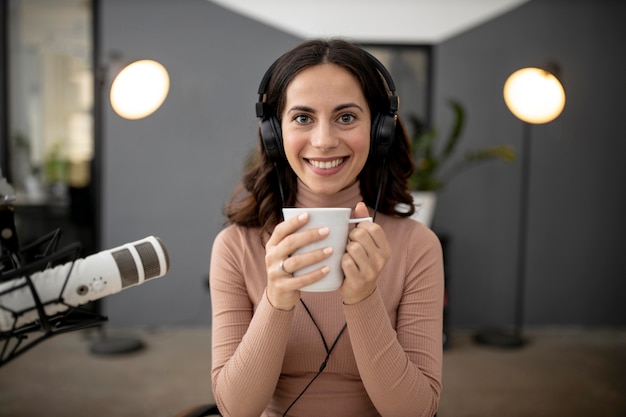 Vooraanzicht van vrouw in een radiostudio met microfoon en koffie