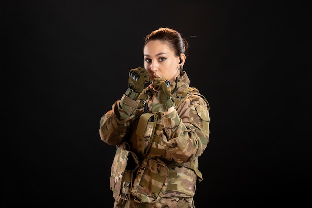 Vooraanzicht van vrouwelijke soldaat in camouflage op de zwarte muur