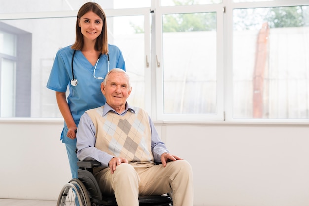 Foto vooraanzicht verpleegster en oude man kijkend naar de camera