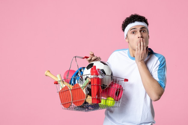 Vooraanzicht verrast jong mannetje in sportkleren met mand vol met sportdingen