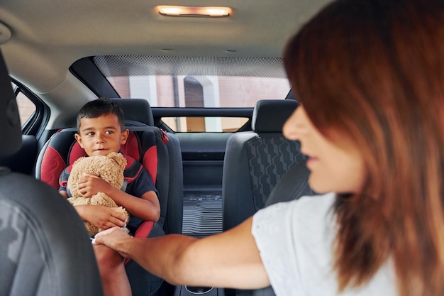 Vooraanzicht vrouw met kleine jongen zit overdag in de moderne auto