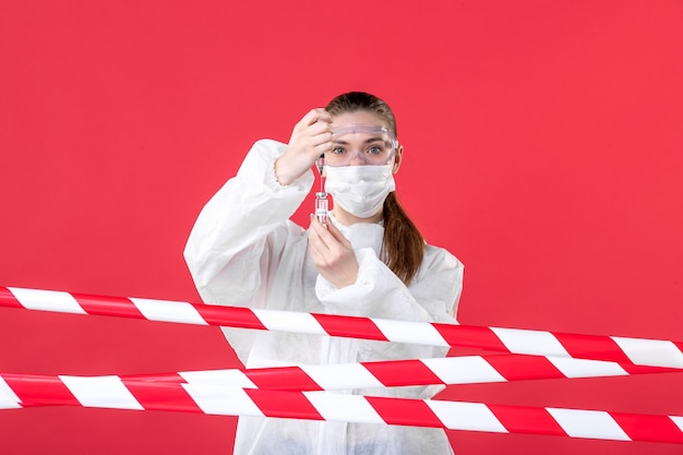 vooraanzicht vrouwelijke arts in beschermend pak die injectie maakt op de rode achtergrond misdaad virus lijn covid- ziekenhuis gezondheid genezen verpleegster emotie