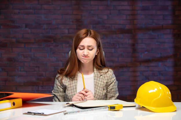vooraanzicht vrouwelijke ingenieur zit achter haar werkplek op de bouwplaats baan agenda onroerend goed zakelijke aannemer bouwer zakelijk succes
