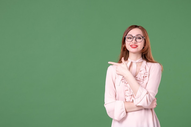 Vooraanzicht vrouwelijke leraar in roze blouse op groene achtergrond school kleur bibliotheek college baan vrouw jong boek les werk