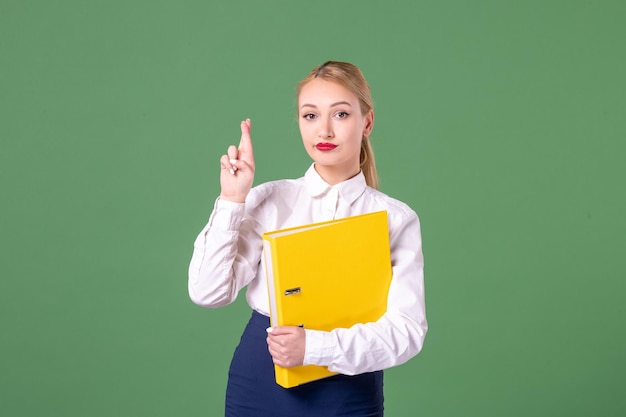 Vooraanzicht vrouwelijke leraar in strikte kleding met gele bestanden op groene achtergrond student universiteit vrouw boek studie bibliotheek werk les