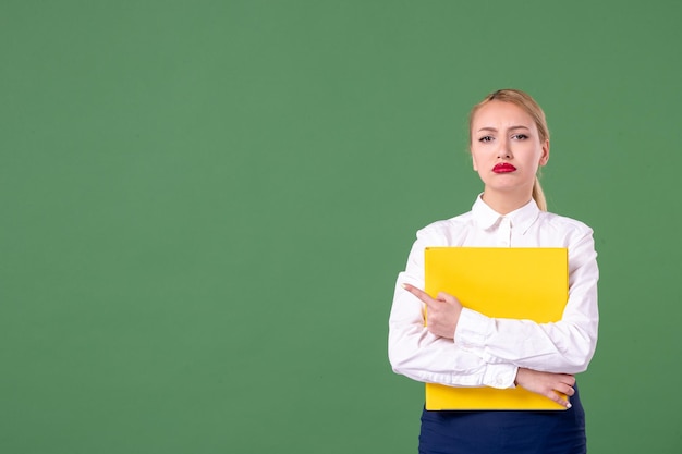 Vooraanzicht vrouwelijke leraar met gele bestanden op groene achtergrond boek studie bibliotheek school werk universiteit vrouw les uniform studenten