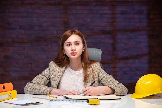 vooraanzicht vrouwelijke werknemer binnen bouwplaats zittend achter tafel met documenten ingenieur aannemer projectmanager corporate plan job