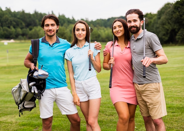 Vooraanzichtgroep golfspelers die bij camera glimlachen