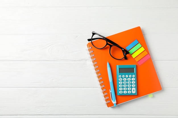 Voorbeeldenboek, glazen, rekenmachine, pen en stickers op houten tafel, ruimte voor tekst