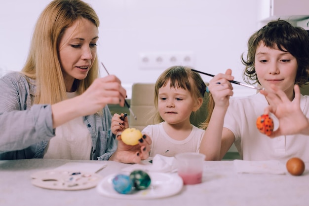 Voorbereiden op Pasen De familie is paaseieren aan het schilderen thuis in de keuken Moeder leert haar dochters tekenen Medium shot