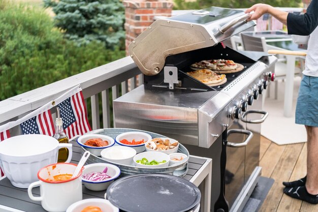 Voorbereiden van individuele gegrilde pizza's op een gasbarbecue buiten.