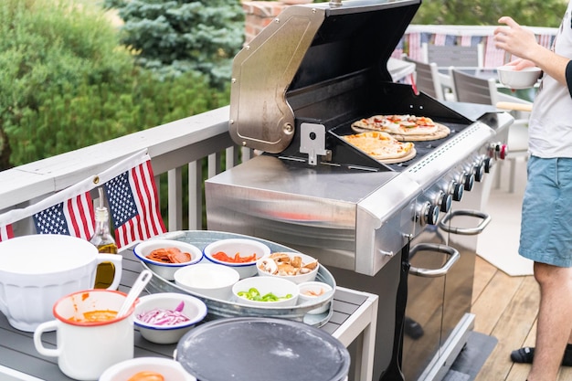 Voorbereiden van individuele gegrilde pizza's op een gasbarbecue buiten.