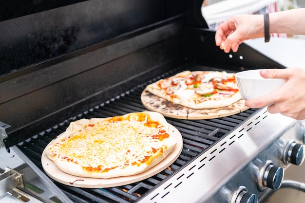 Voorbereiden van individuele gegrilde pizza's op een gasbarbecue buiten.