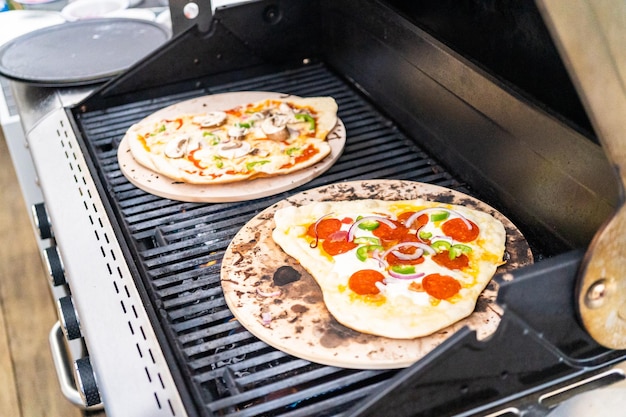 Voorbereiden van individuele gegrilde pizza's op een gasbarbecue buiten.