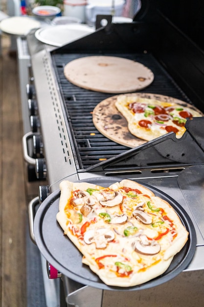 Voorbereiden van individuele gegrilde pizza's op een gasbarbecue buiten.