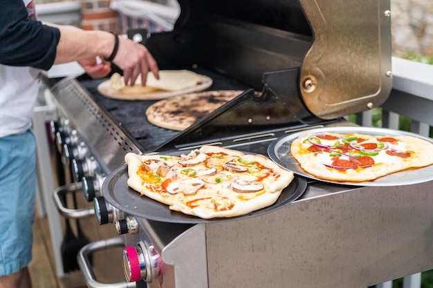 Voorbereiden van individuele gegrilde pizza's op een gasbarbecue buiten.