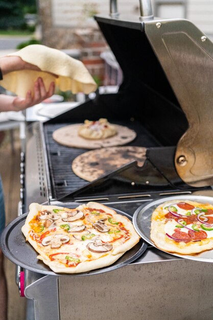 Voorbereiden van individuele gegrilde pizza's op een gasbarbecue buiten.