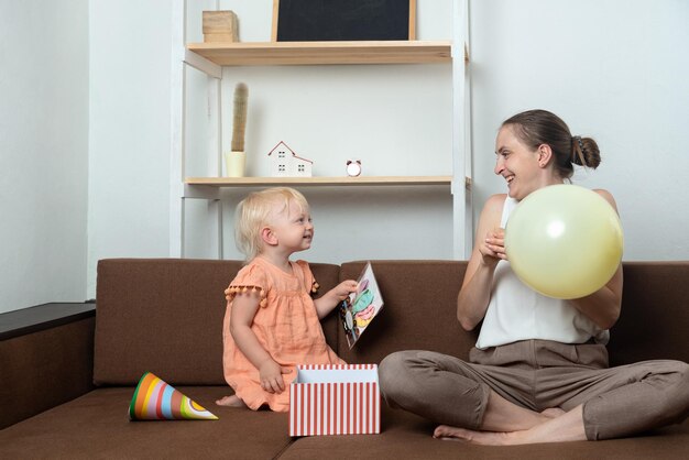 Voorbereiding op de vakantie Moeder en baby spelen thuis met een ballon op de bank