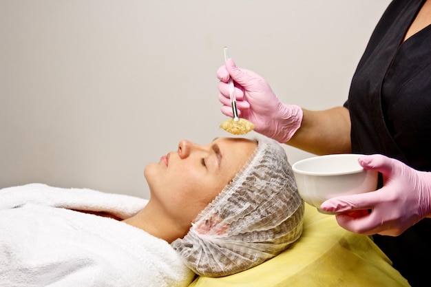 Voorbereiding op procedures in het kantoor van de schoonheidsspecialist waarbij de gel met een speciale borstel op het gezicht wordt aangebracht