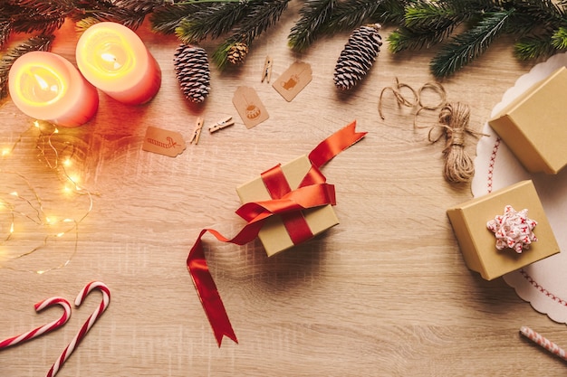 Voorbereiding van de kerstcadeaudoos met rood lint en rustieke decorspullen op een houten achtergrond