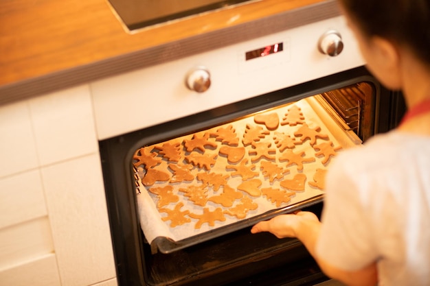 Foto voorbereiding van desserts zet het meisje in de oven een bakplaat met peperkoekkoekjes om te koken