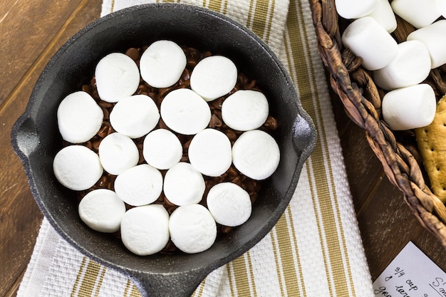 Voorbereiding van smores dip bereid met grote marshmallows in gietijzeren pan.