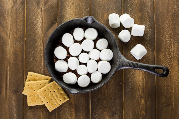 Voorbereiding van smores dip bereid met grote marshmallows in gietijzeren pan.