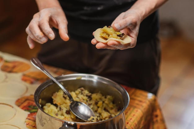 Voorbereiding van varines Onherkenbare vrouw doet vulling in deeg Dumplings beeldhouwen