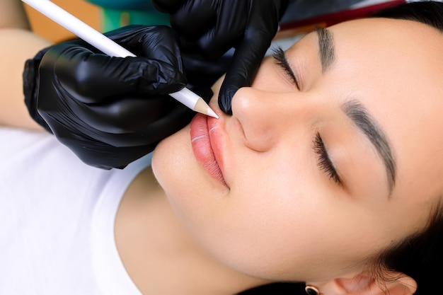 Voorbereiding voor de procedure van permanente make-up van de lippen markeren met een wit potlood op de lippen