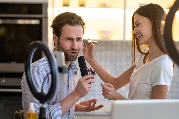 Voorbereiding. Vrouwelijke stylist doet make-up bij een journalist voordat hij uitzendt