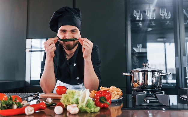 Voorbereidingsproces Professionele jonge chef-kok in uniform die aan de keuken werkt