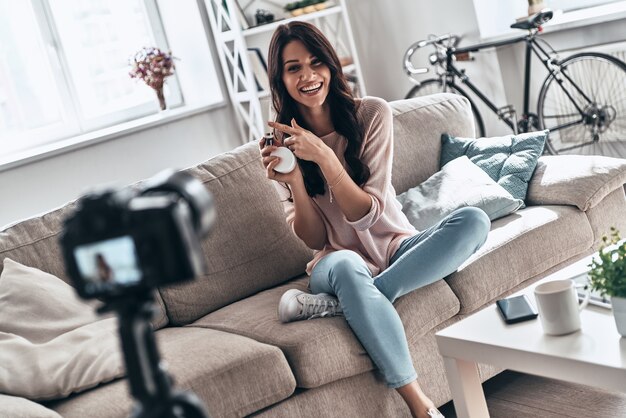 Voordelen van producten delen. Mooie jonge vrouw die schoonheidsproducten vasthoudt en glimlacht terwijl ze video op sociale media maakt