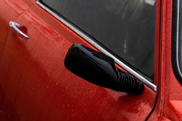 Voordeur detail van een rode retro auto in regendruppels close-up