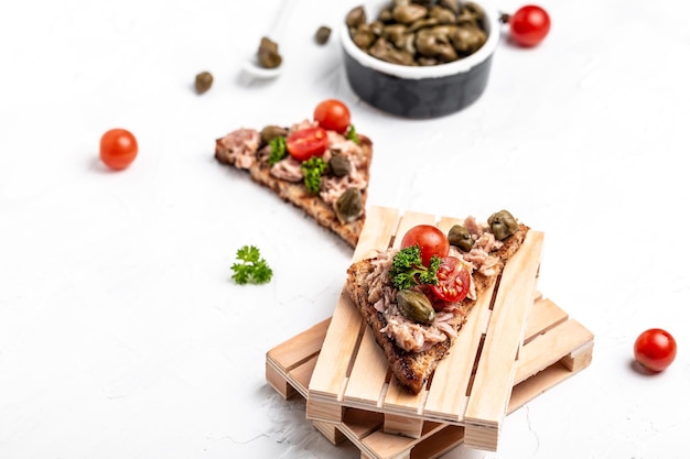 Voorgerecht bruschetta met tonijn Italiaanse bruschetta sandwiches met ingeblikte tonijn, tomaten en kappertjes toast met tonijn heerlijk gezond eten op een donkere achtergrond Bovenaanzicht plat lag